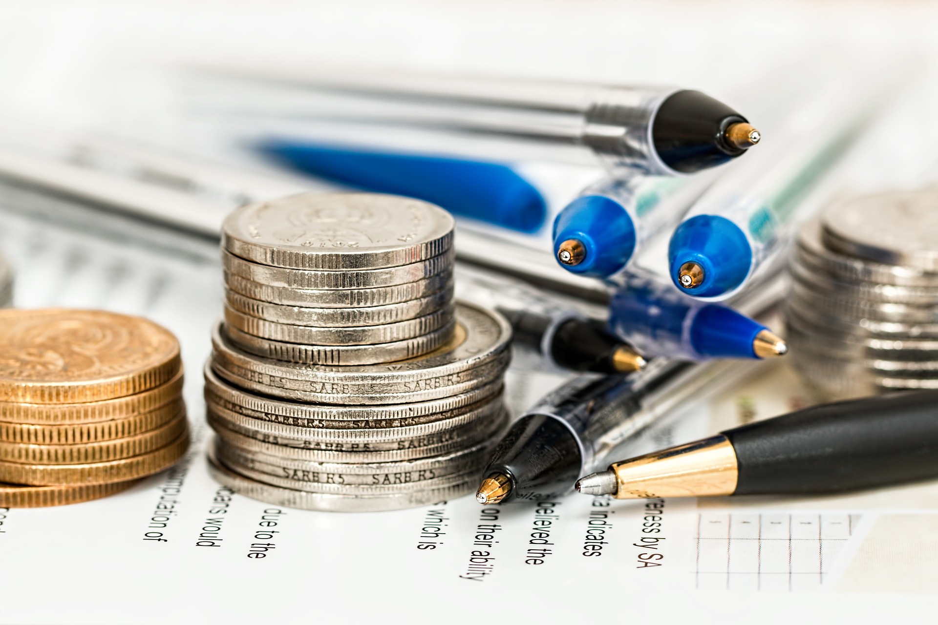 Stacks of pens and coins on a sheet of paper